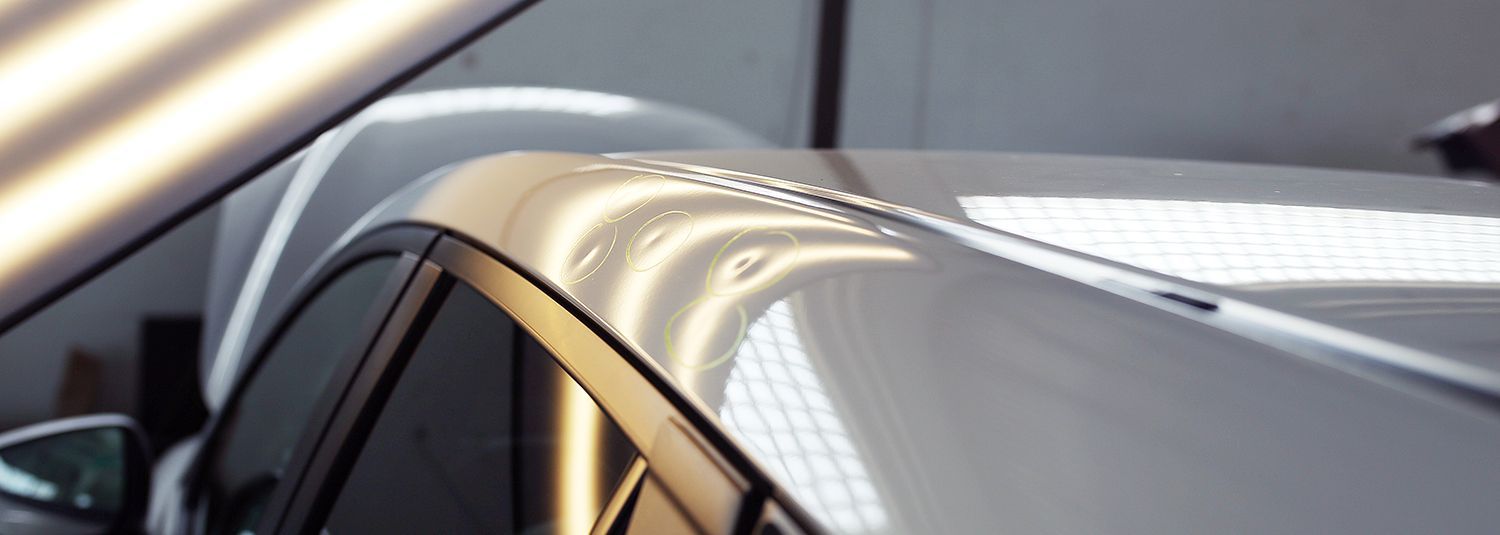 Close-up of a silver car roof with reflections and a visible side window frame.