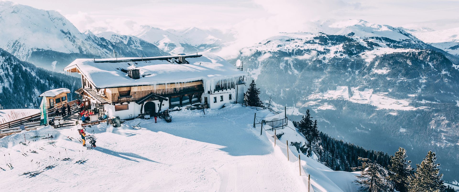 A snowy landscape with a ski resort in the foreground and mountains in the background.