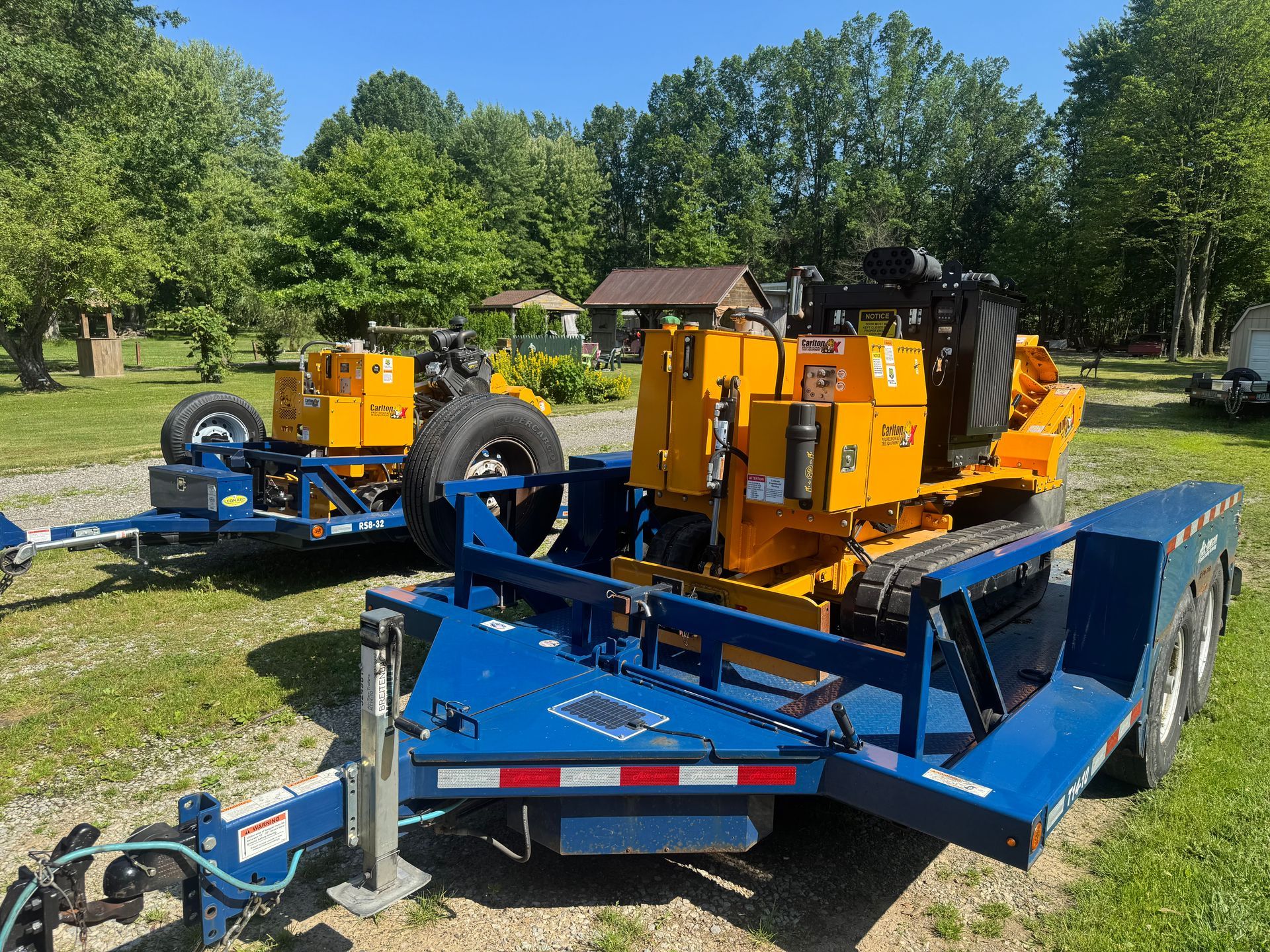 A man wearing a hard hat and safety glasses is holding a chainsaw.