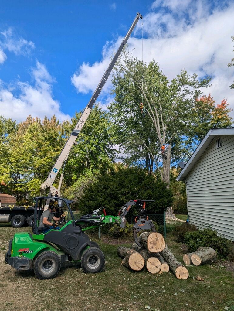 A man is driving a tractor next to a crane in a yard.
