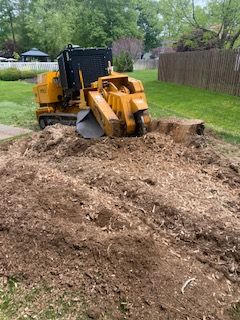 A stump grinder is cutting a tree stump in a yard.