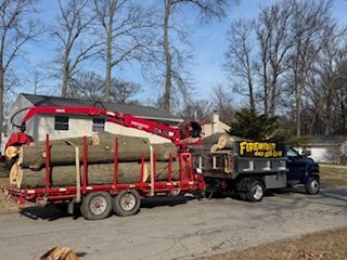 A truck with a crane attached to it is carrying logs.