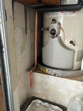 A water heater is sitting on a shelf in a room.