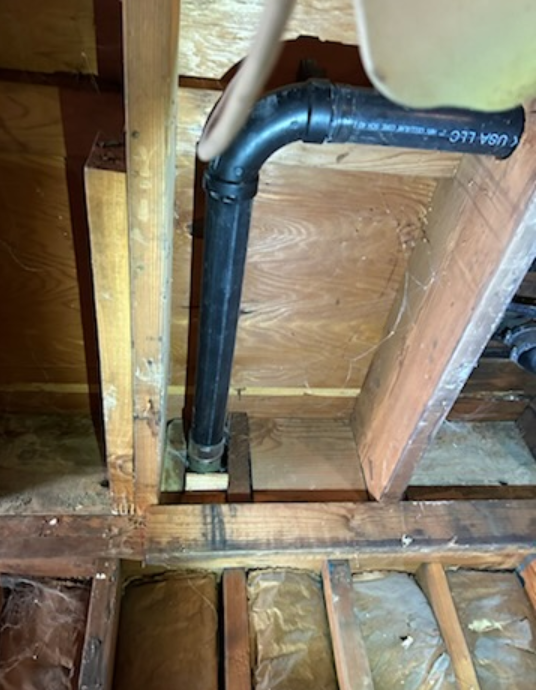 A black pipe is hanging from the ceiling in a wooden room.