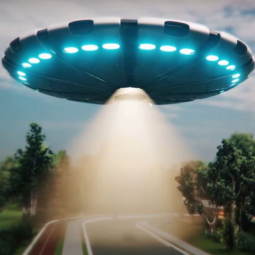 An ufo is flying over a road with trees in the background
