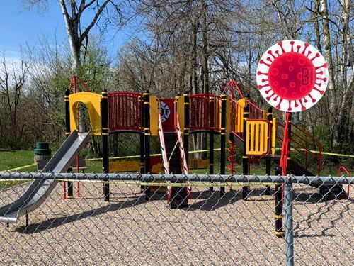 Playground closed with caution tape and a coronavirus sign.