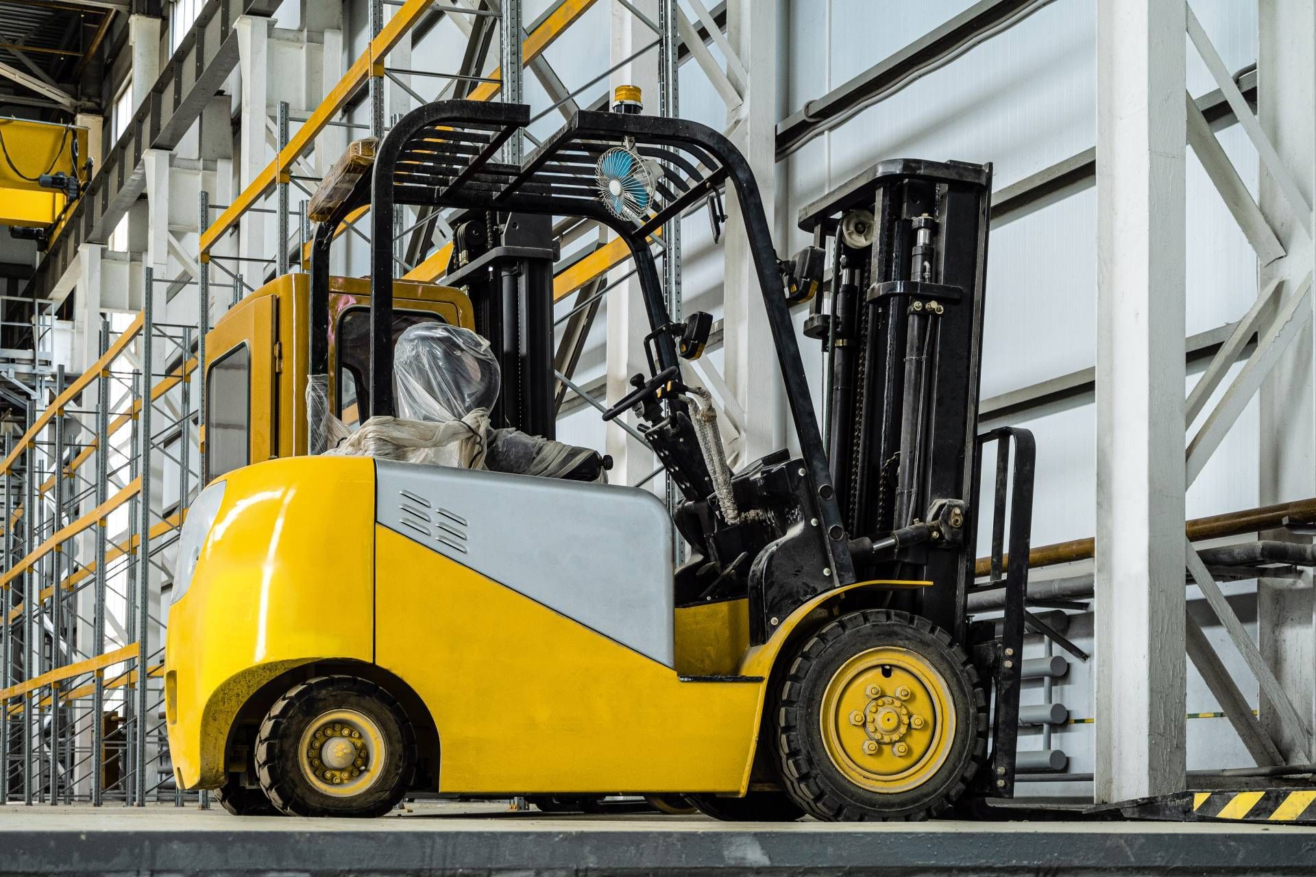 Yellow and gray forklift in an industrial setting, ready for use.