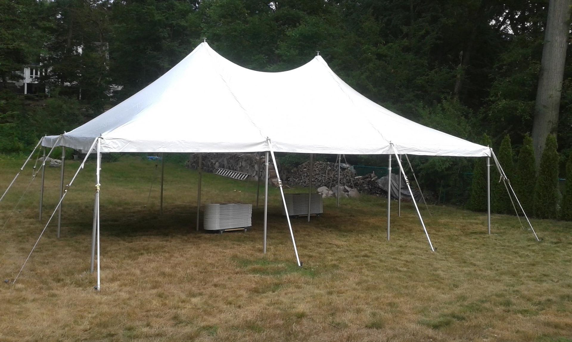 Long wedding reception tables set outdoors with floral arrangements, string lights, and gold chairs.