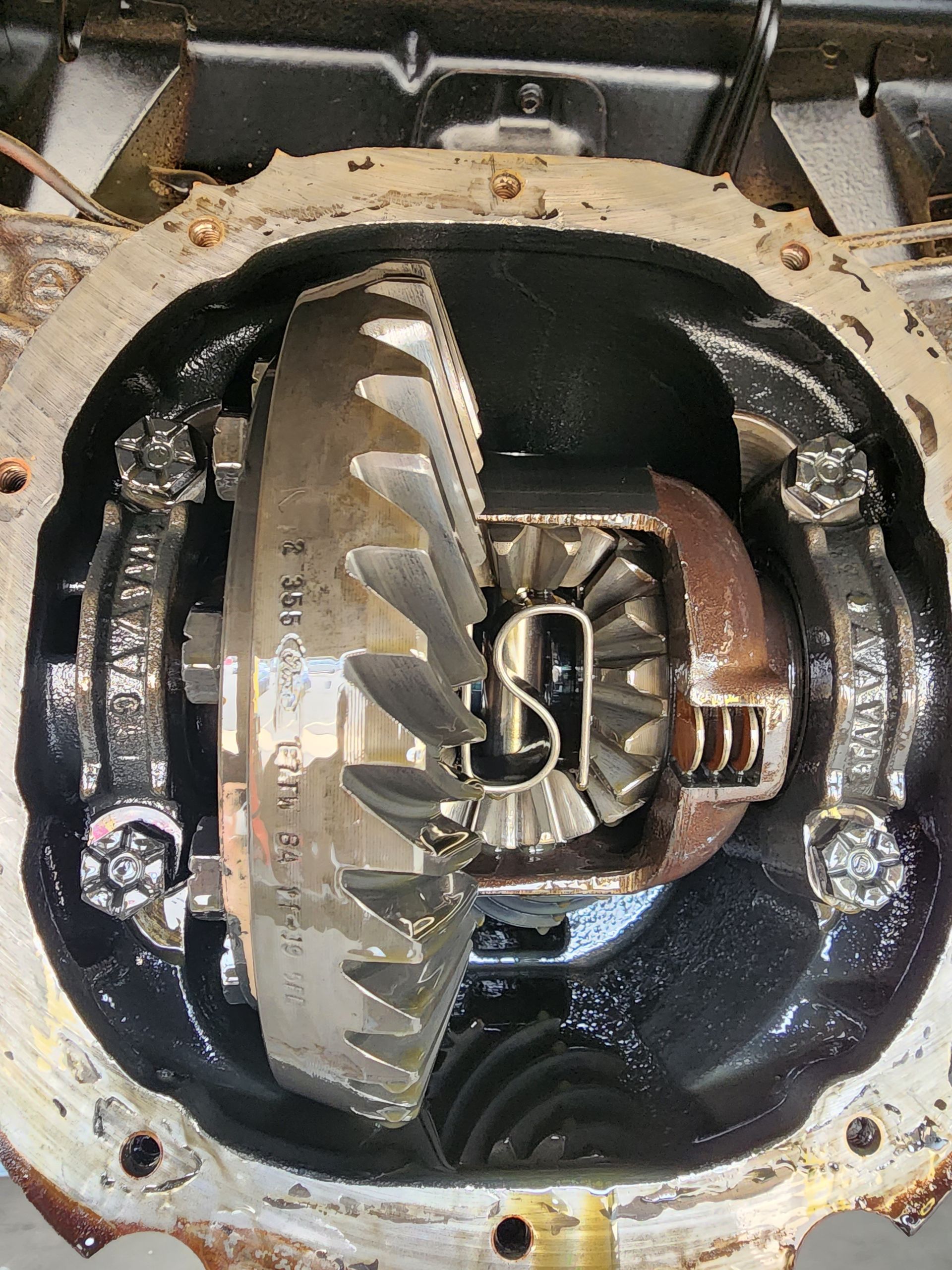 Mechanic disassembling a car transmission with a screwdriver in a workshop.