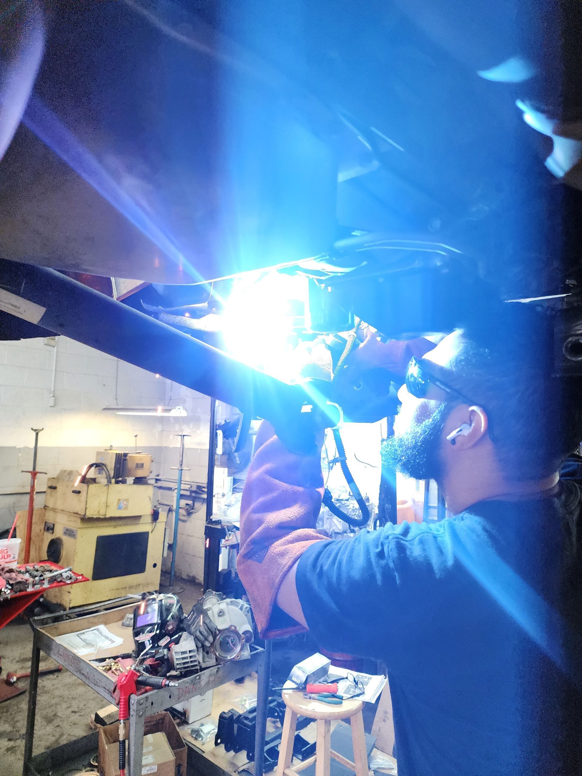 Mechanic in blue overalls working on a car engine in a garage.