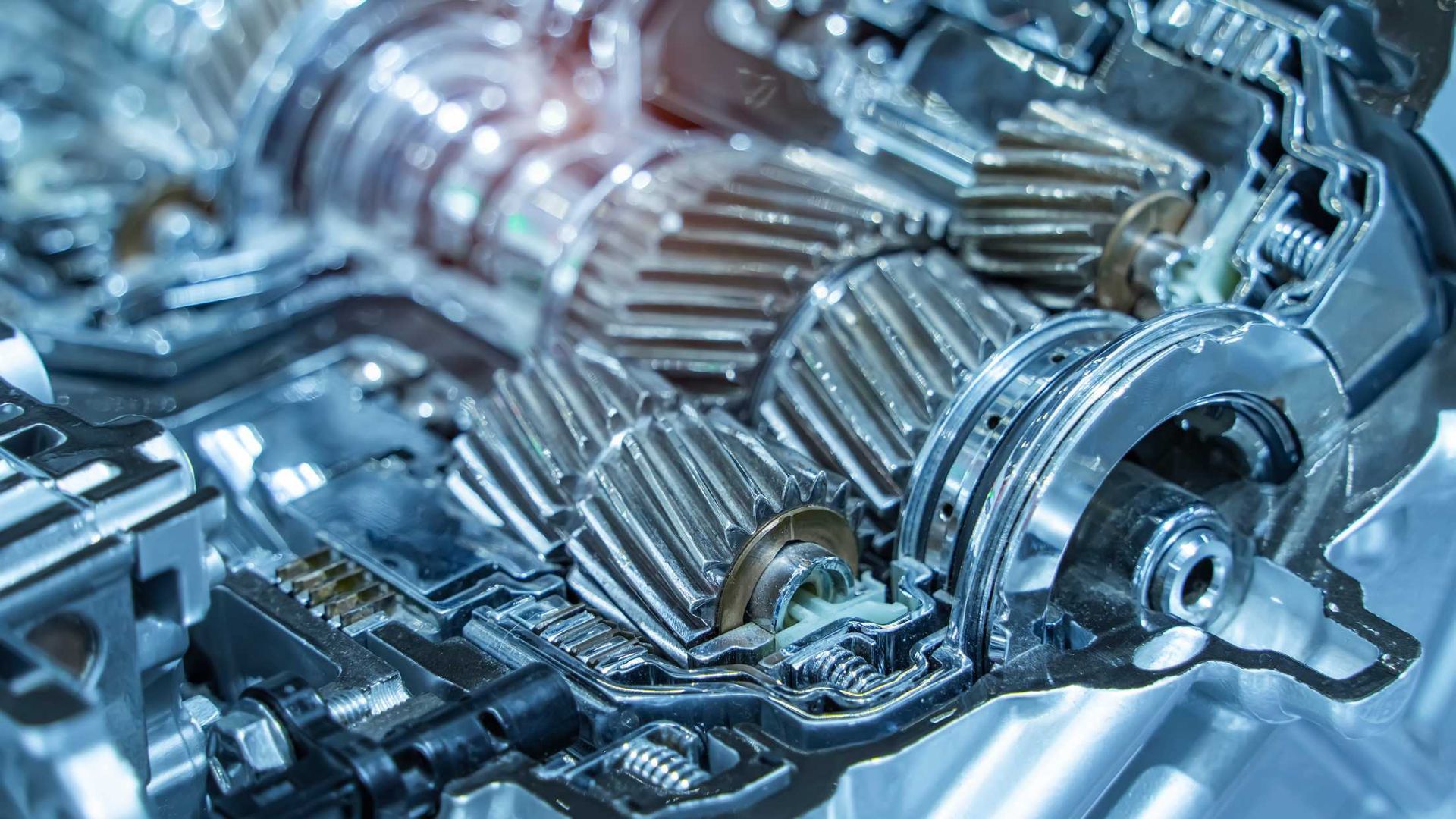 Cutaway view of a metallic gearbox with multiple gears, showcasing internal mechanisms.