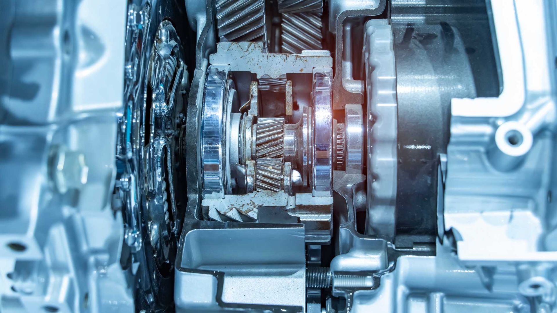 Cutaway view of a car transmission showing gears and internal components in a metallic housing.