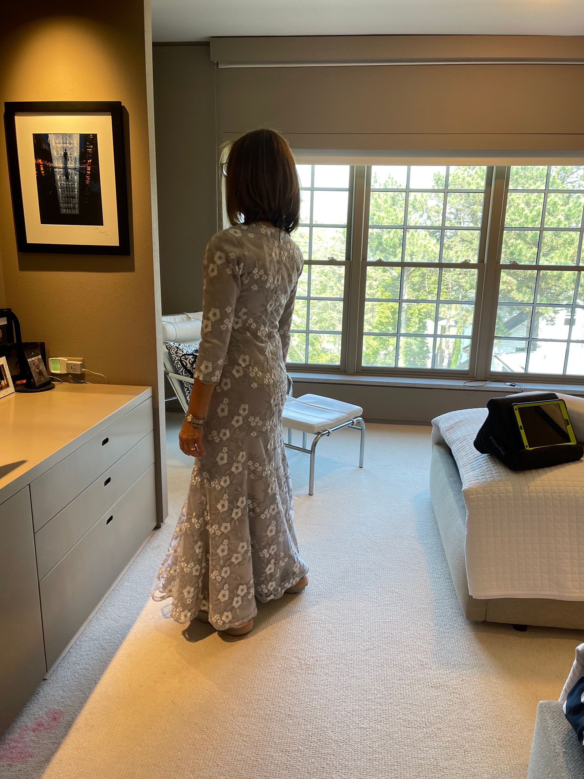 Person's back in white dress being fastened by a hand, focus on large bow detail and zipper.