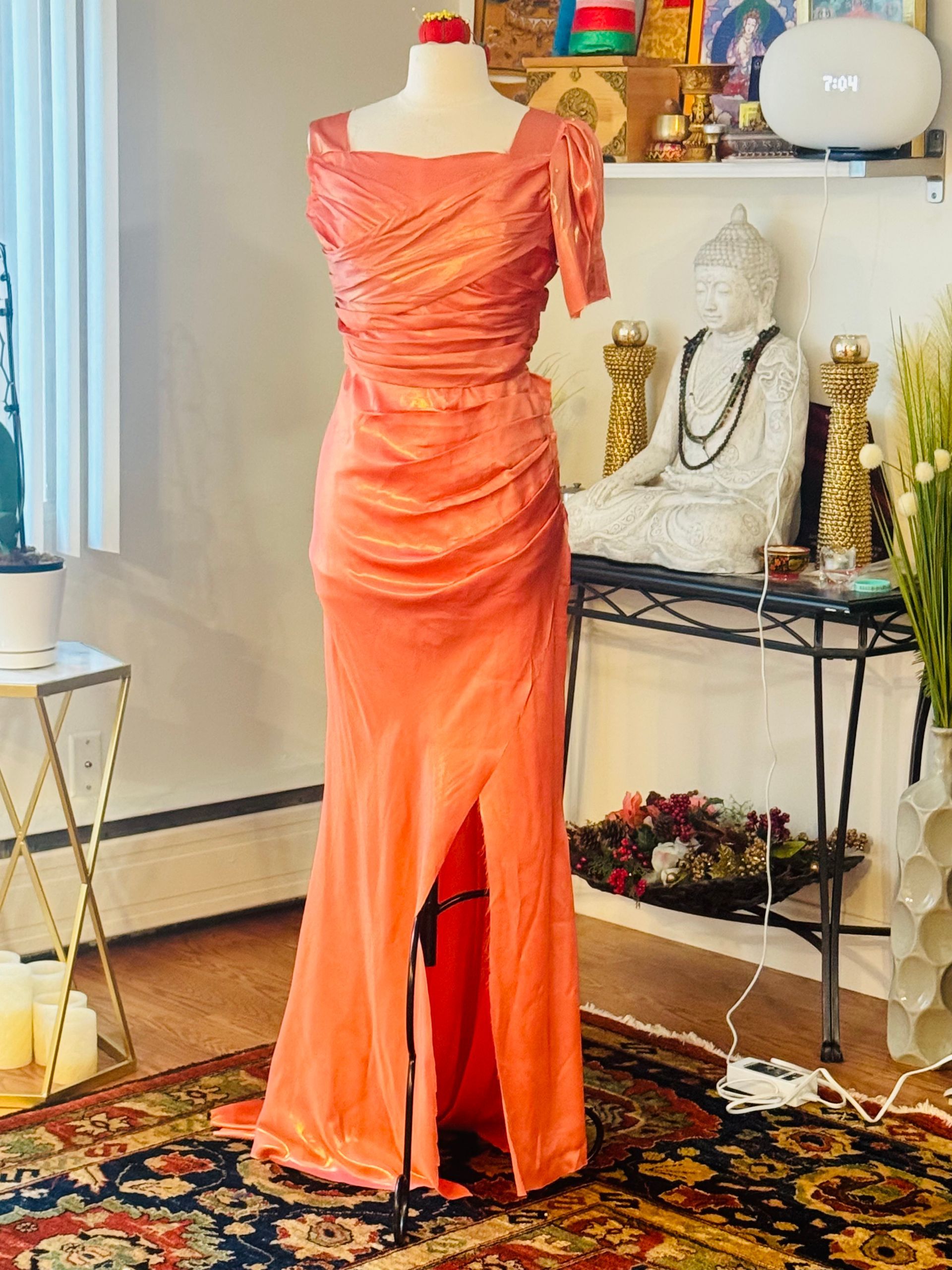Six sequined and flowing bridesmaid dresses in shades of pink and gold hanging in a closet.