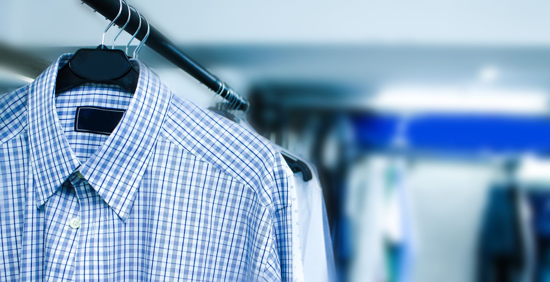 Blue plaid shirt hanging on a rack in a store. Blurred background.