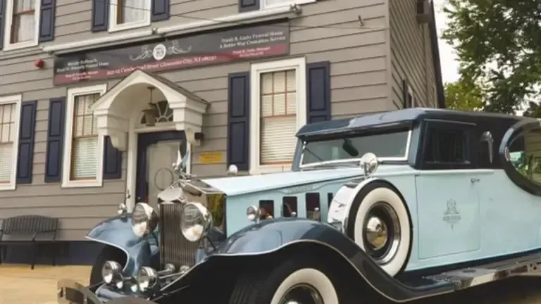 Vintage blue-and-black classic car parked in front of a historic building