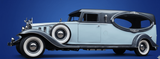 Vintage light blue classic car with black roof and whitewall tires, shown in side view.