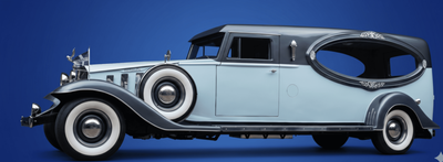 Vintage light blue classic car with black roof and whitewall tires, shown in side view.