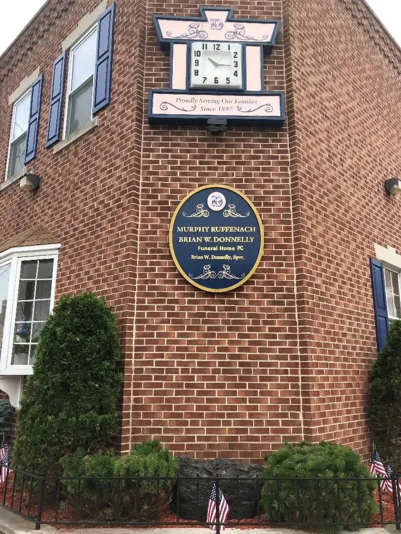 Brick building corner with blue historic marker plaque and clock above windows