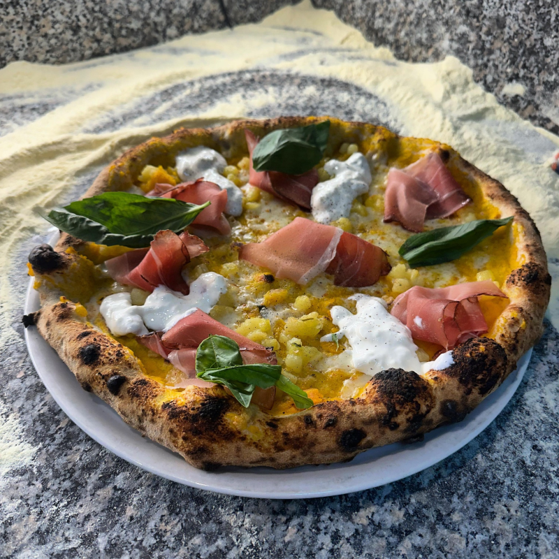 Una pizza con tanti condimenti è su un piatto.