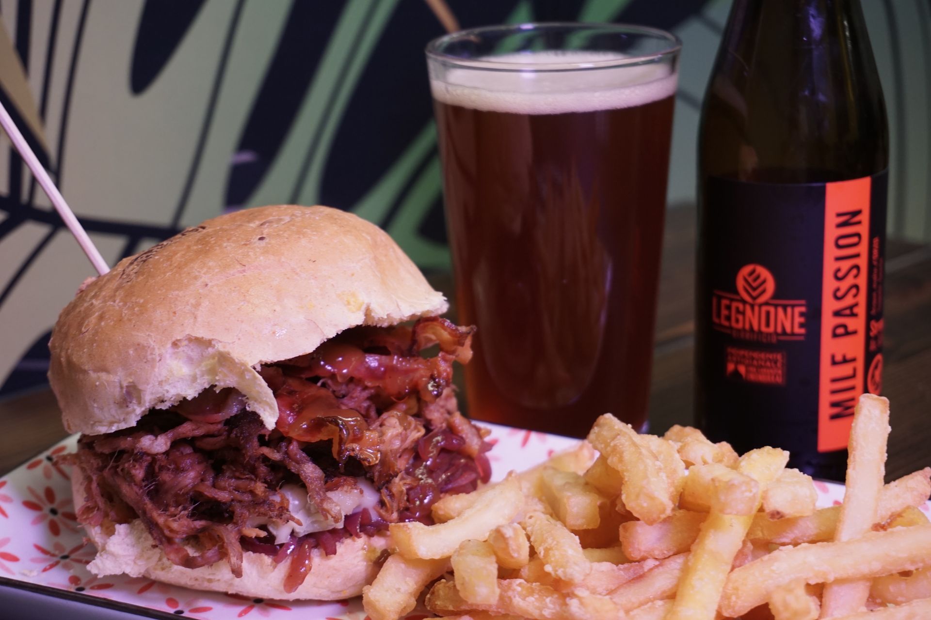 Un hamburger e delle patatine fritte sono su un piatto accanto a un bicchiere di birra.