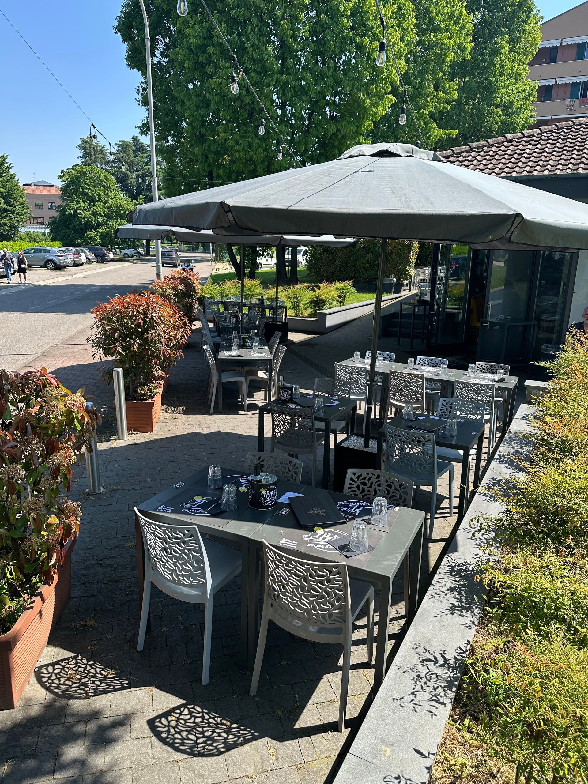 Un patio con tavoli e sedie sotto gli ombrelloni nelle giornate di sole.