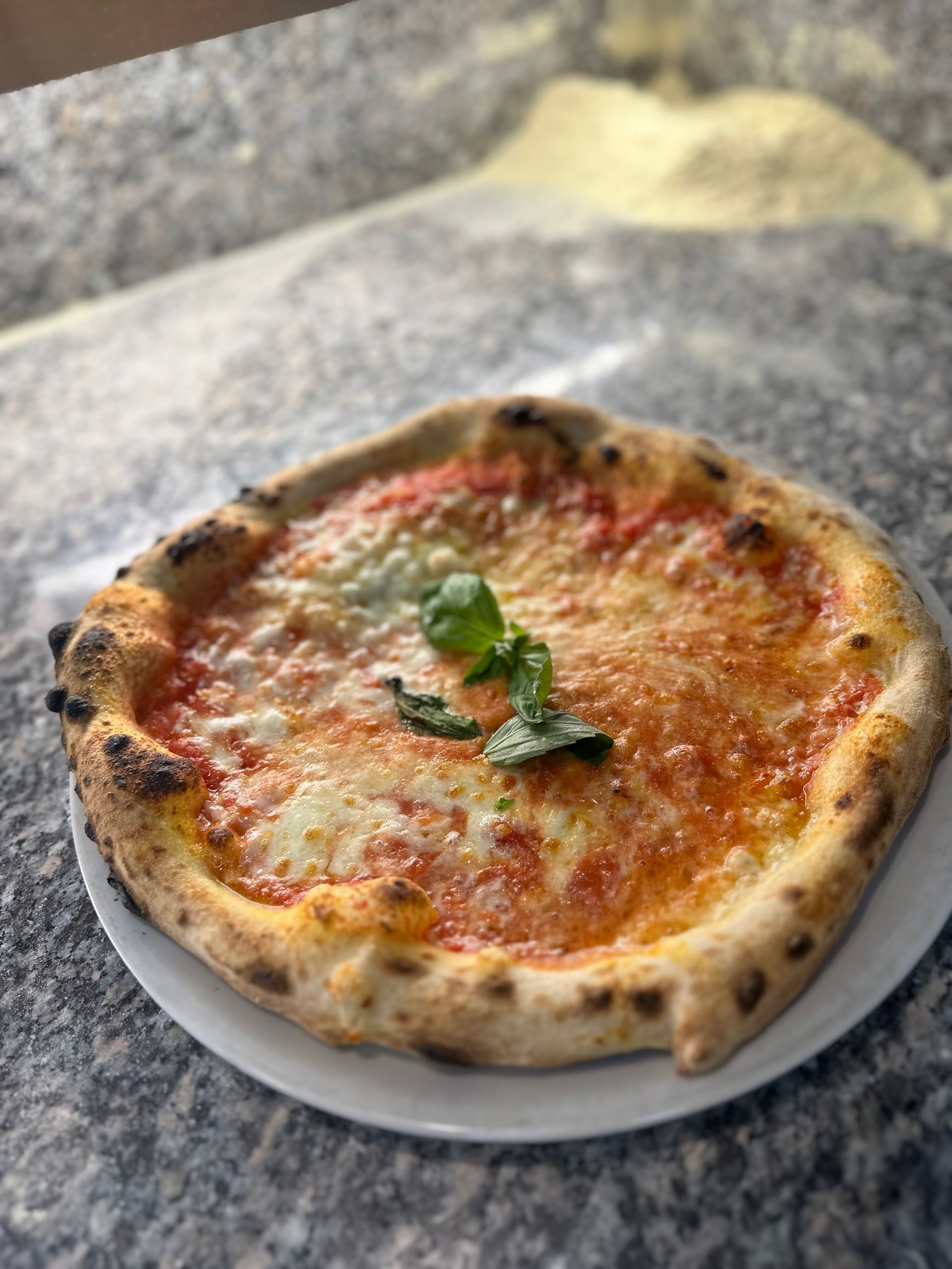 Una pizza è appoggiata su un piatto bianco su un tavolo.