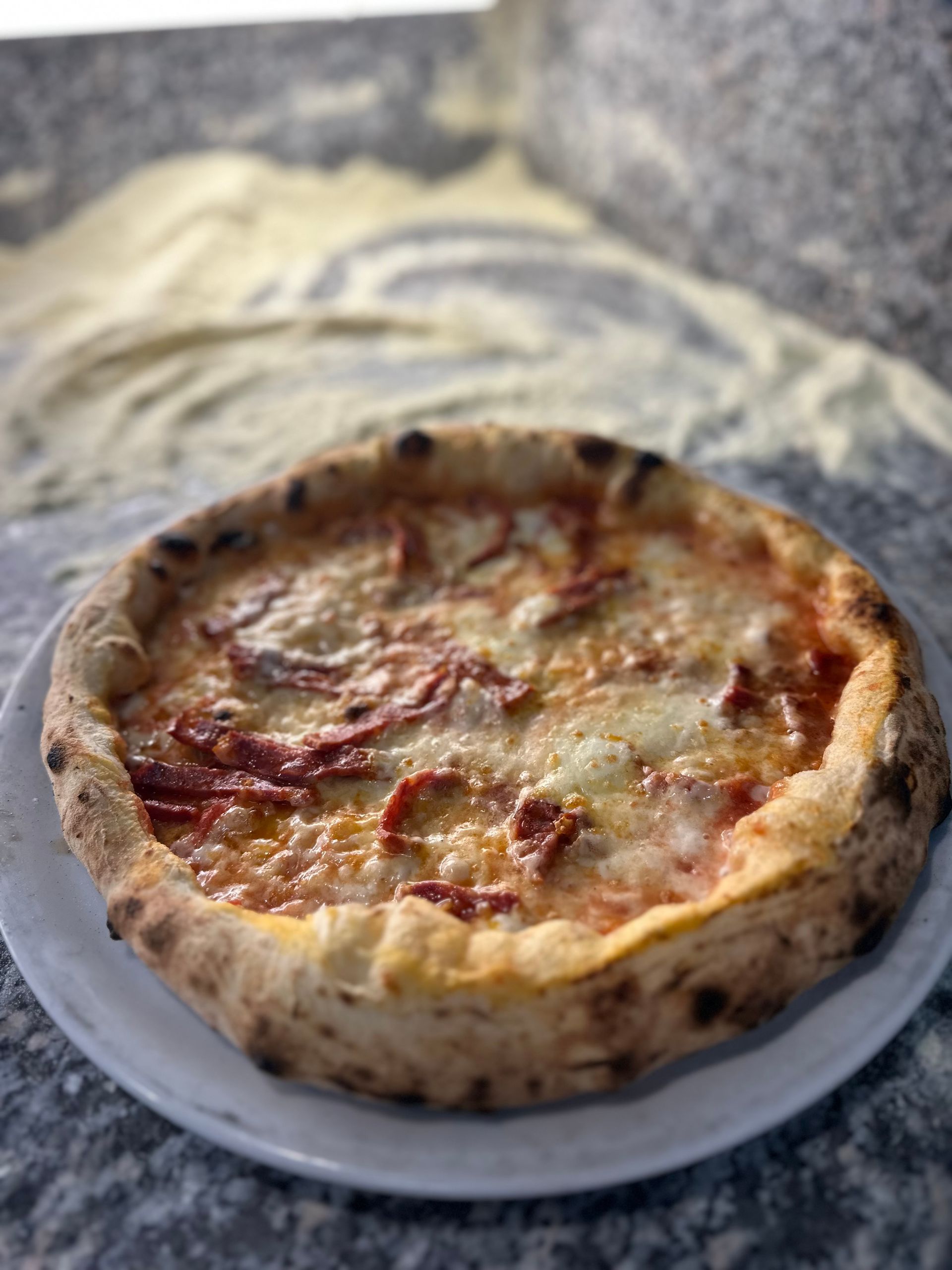 Una pizza è appoggiata su un piatto bianco su un tavolo.