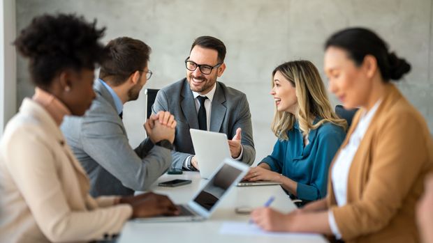 A group of business people are sitting around a table having a meeting.