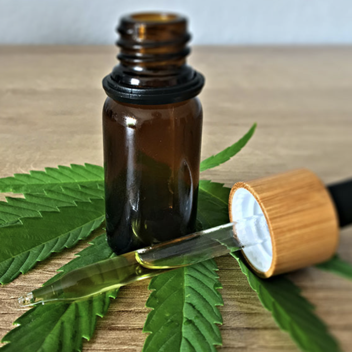 Picture of a cannabis leaf and a tincture bottle with a dropper.