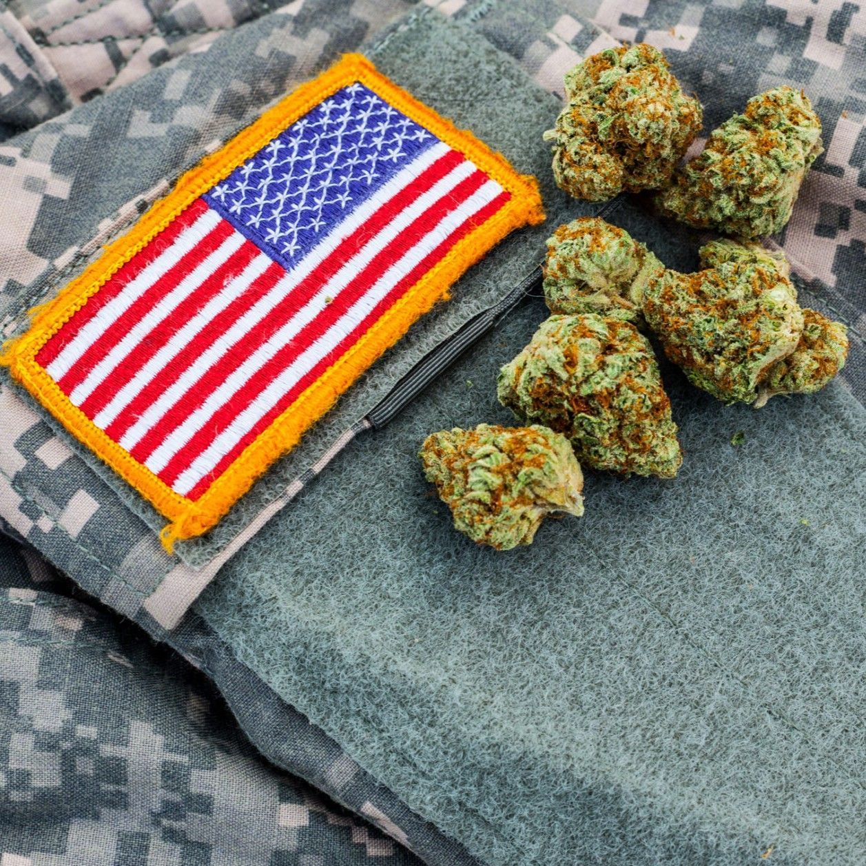 Picture of urban military uniform with a US Flag patch on it and cannabis nugs set next to the patch