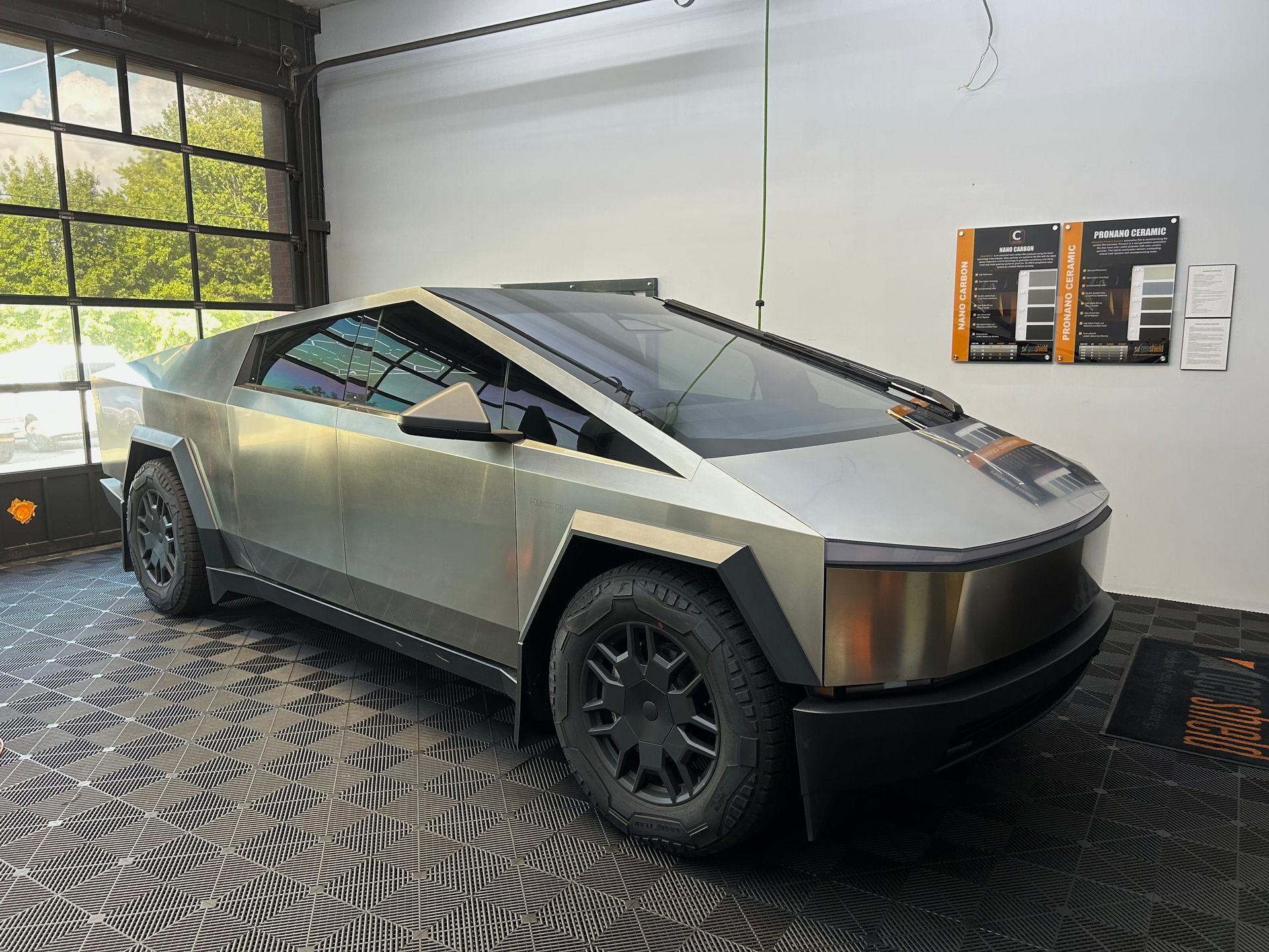A silver tesla cybertruck is parked in a garage.