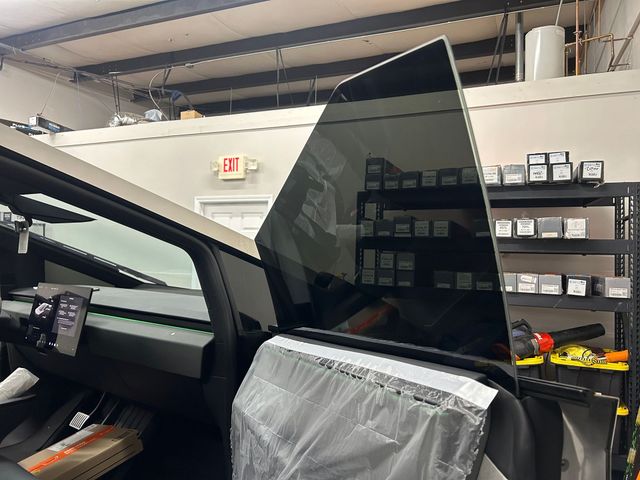 A tesla model 3 is sitting in a garage with its window open.