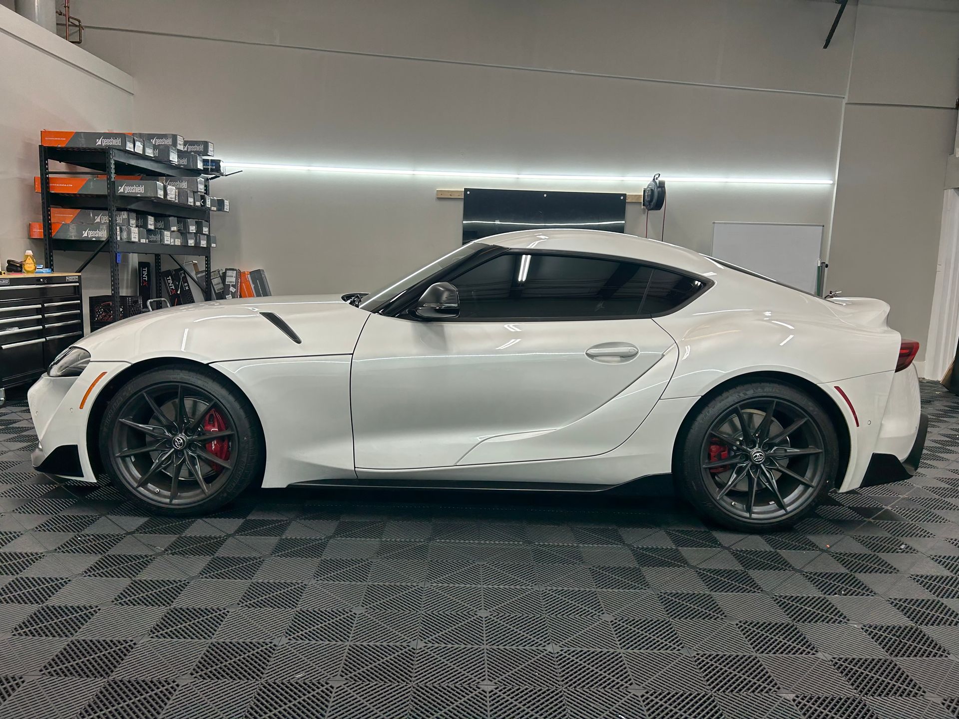 A white toyota supra is parked in a garage.