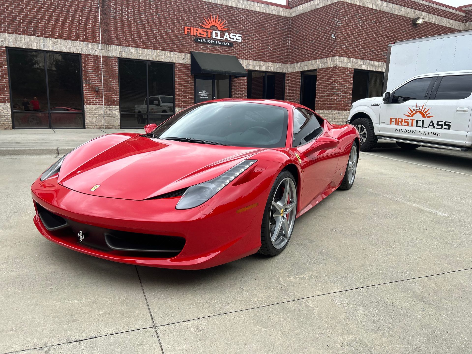A red ferrari 458 italia is parked in front of a building.