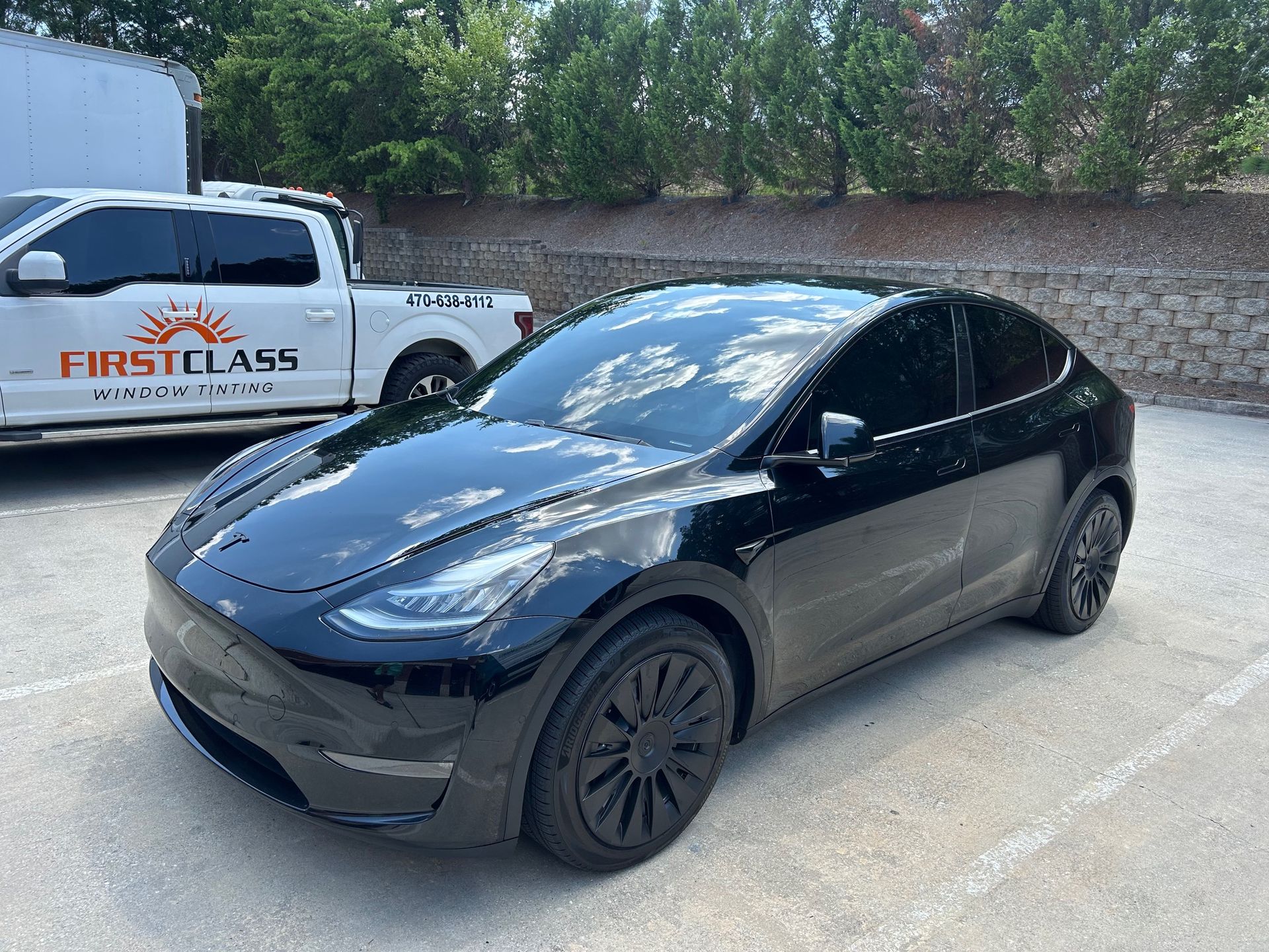 A black tesla model y is parked in front of a brick building.