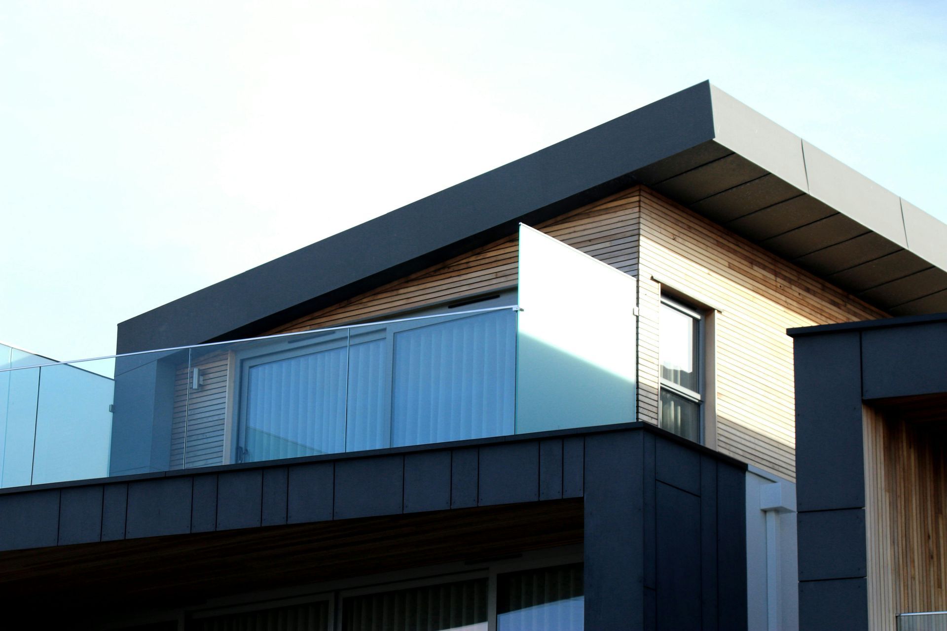 A modern house with a balcony and a glass railing.