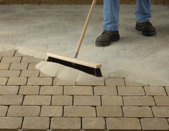 Large Broom Sweeping in  polymeric sand to bind pavers