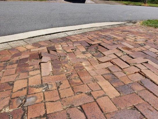 dangerous trip hazards located on Damaged Driveway with uneven Pavers