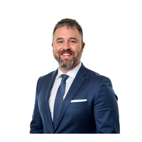Smiling man in a blue suit and tie, white shirt, with a dark beard, against a white backdrop.