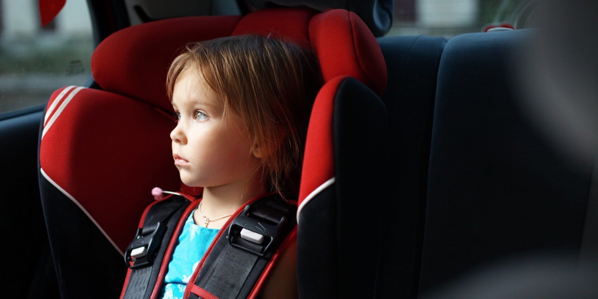 A little girl is sitting in a car seat.