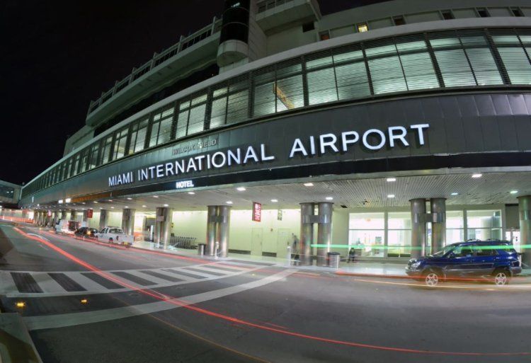 A car is driving past the miami international airport at night.