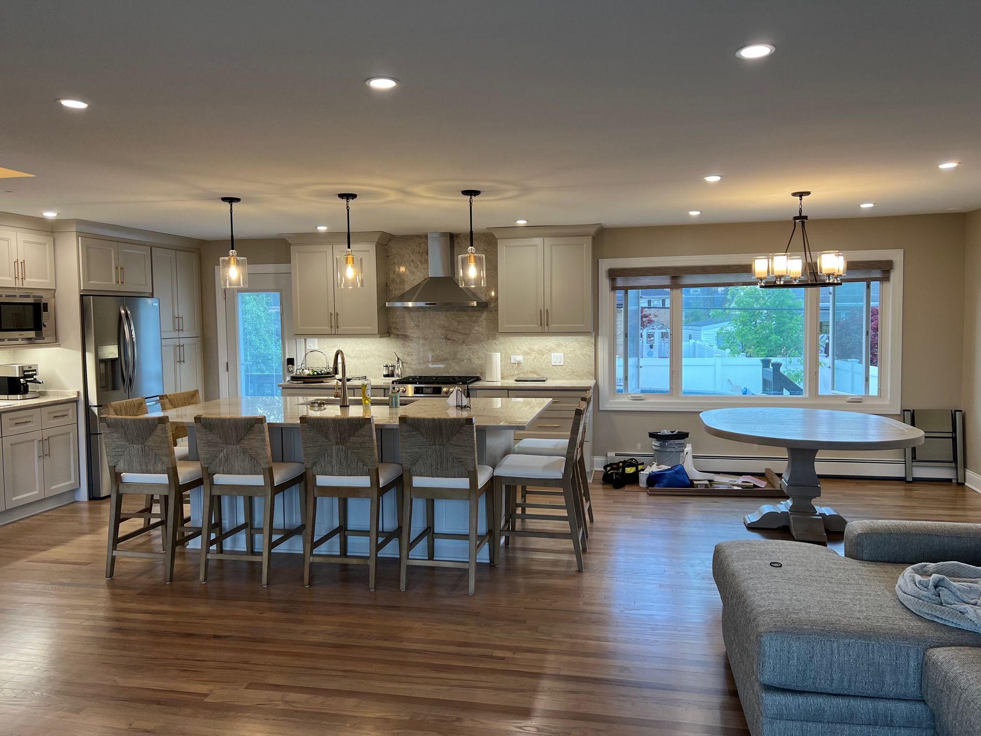 Spacious kitchen with island seating, stainless steel appliances, and a round dining table near a window.