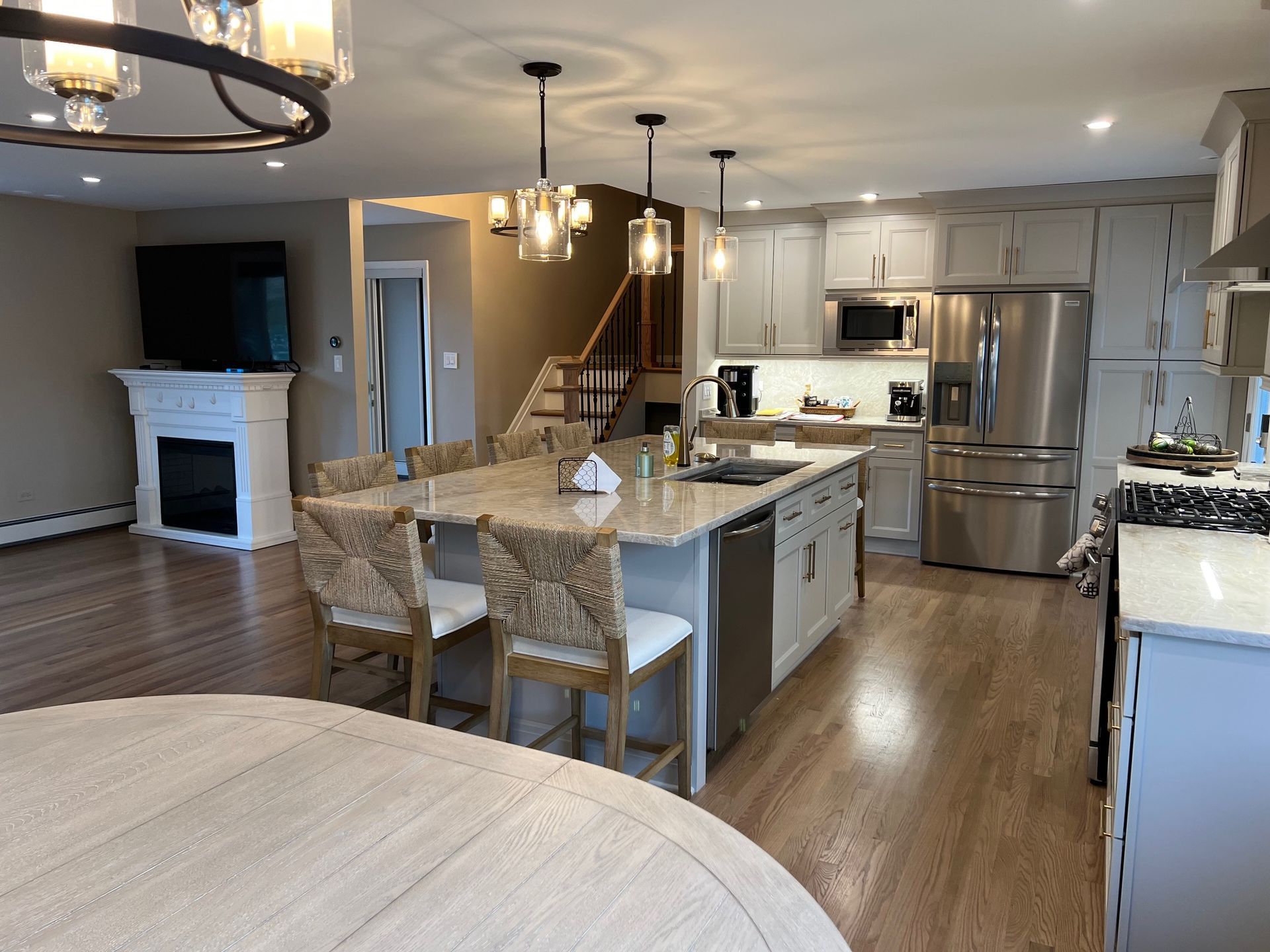 A modern kitchen with an island and seating, hardwood floors, and stainless steel appliances.