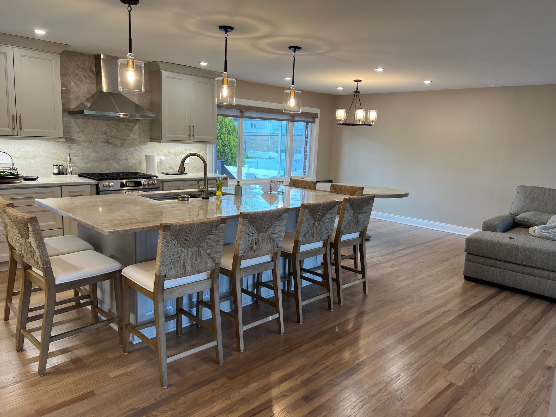 Modern kitchen with island seating, wood floors, and neutral-toned cabinetry.