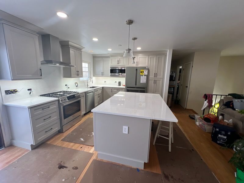Newly renovated kitchen with gray cabinets, stainless steel appliances, and a white countertop island.
