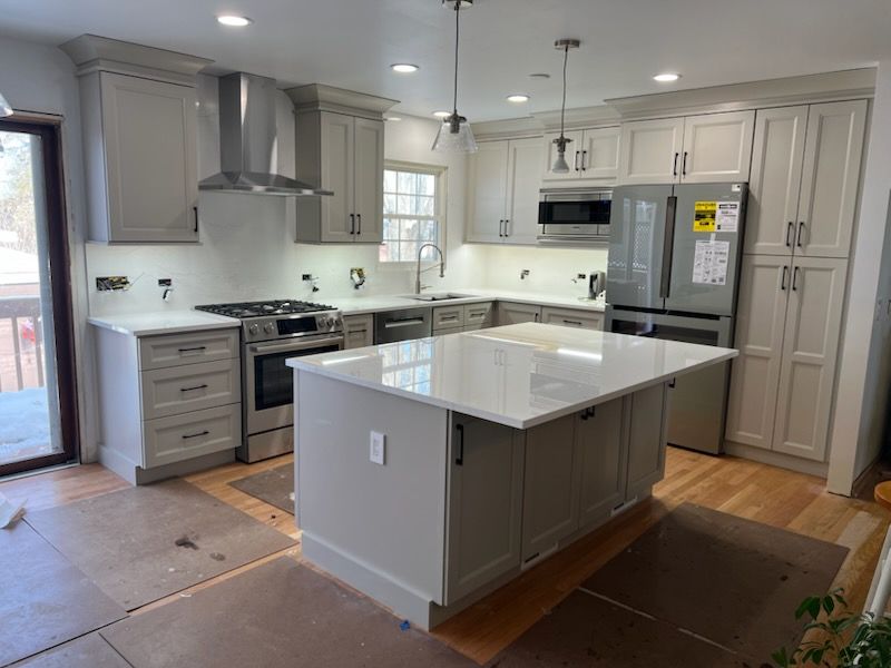 Newly renovated kitchen with light gray cabinets, stainless steel appliances, and white countertops.