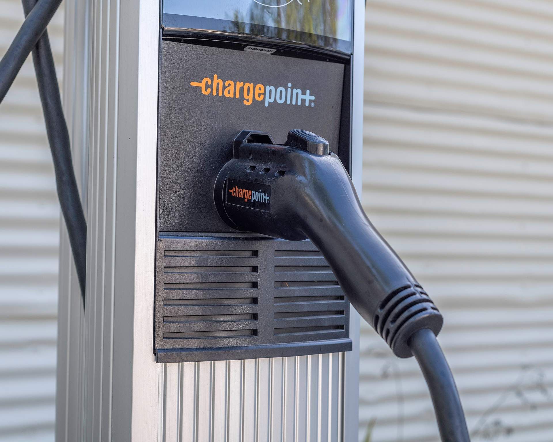 Electric vehicle charging station with a black charging cable.