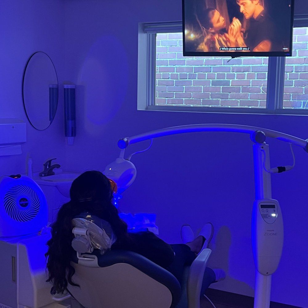 A Woman is Sitting in a Dental Chair in Front of a Television - Buffalo, NY - Hertel Family Dentistry