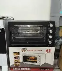 Horno eléctrico negro con perillas de control, en su caja, contra una pared blanca.